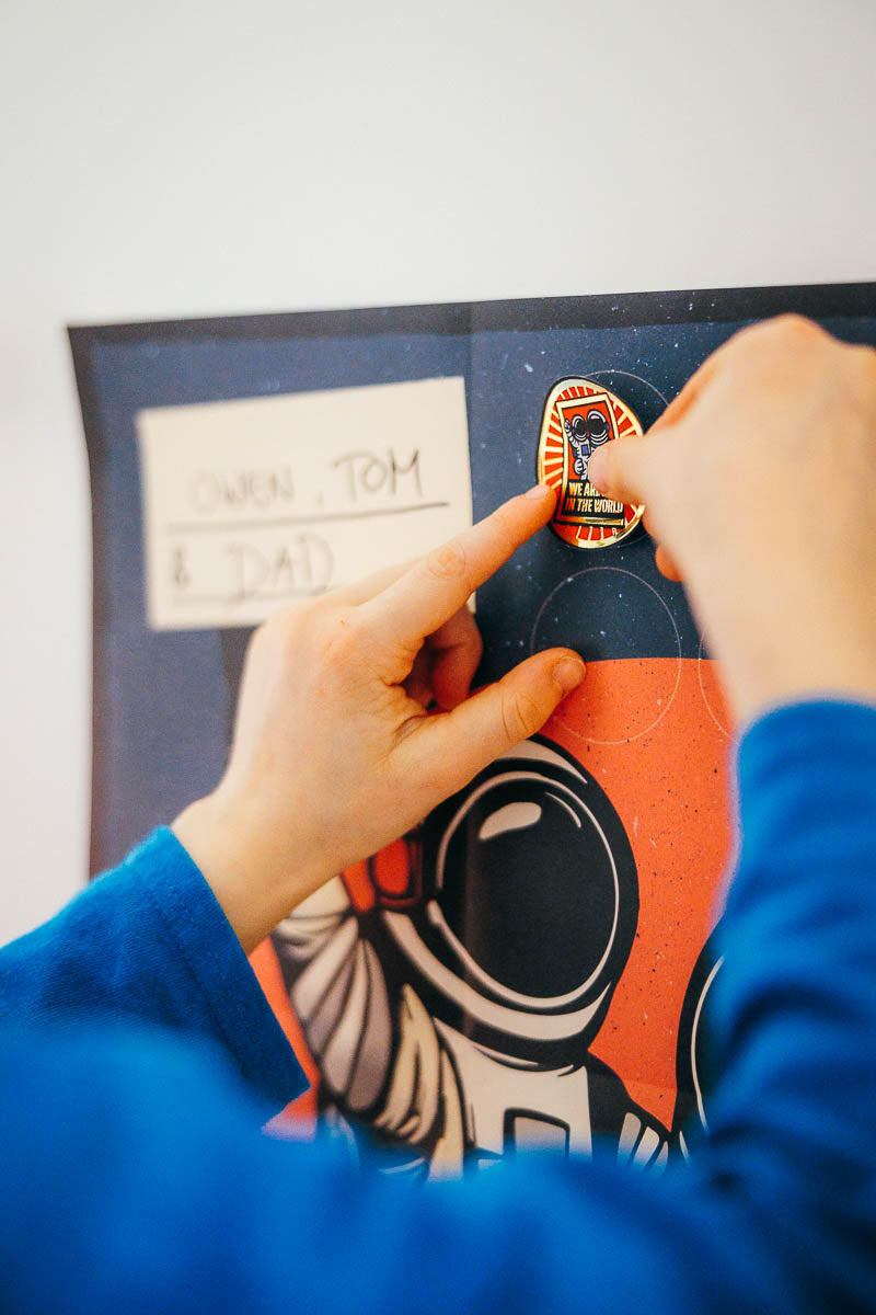 Person placing a mission badge on the I AM BEST Dad in the world achievement poster.