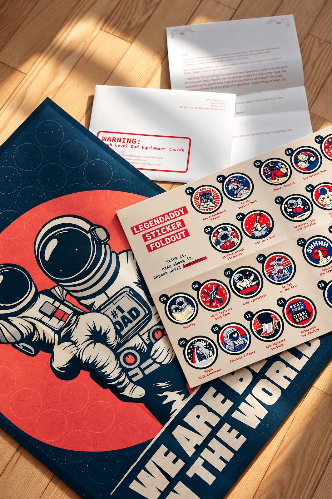 Astronaut poster 'We are best in the world' with a Legendary Sticker Foldout sheet, a letter and an envelope on a wooden floor